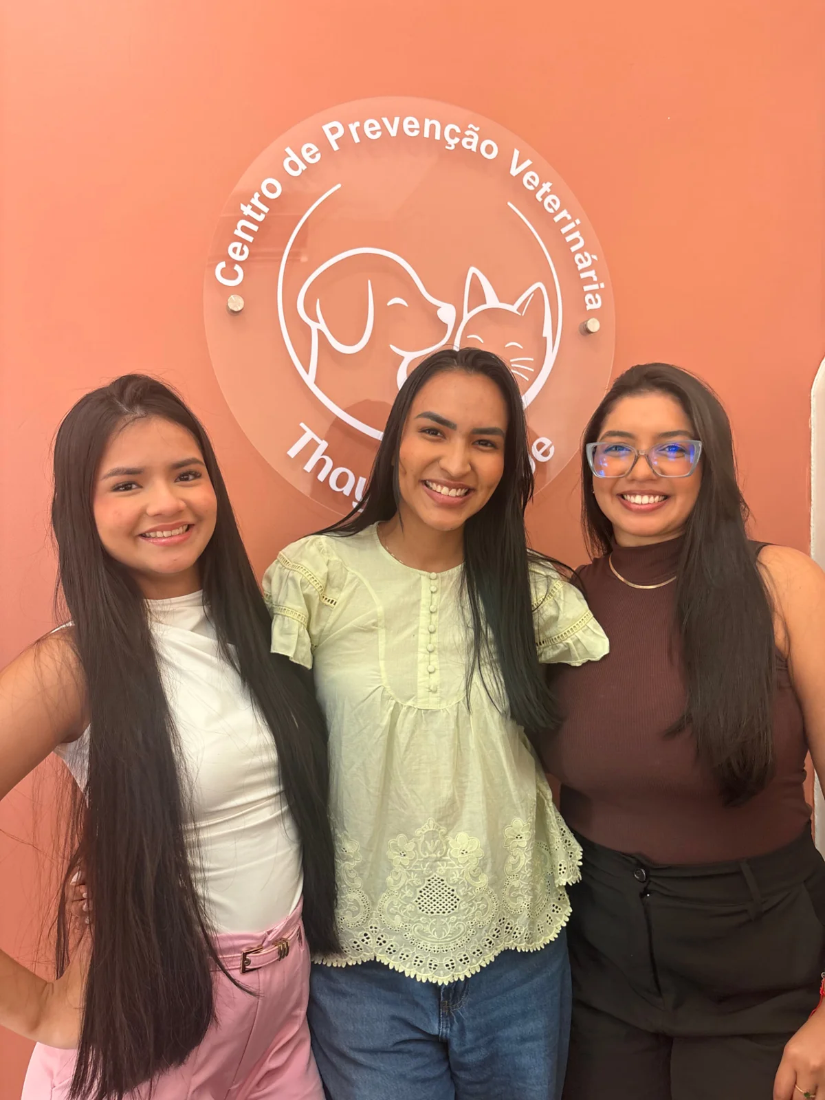 Três mulheres em frente à identificação da clínica CPV Thays Abbade